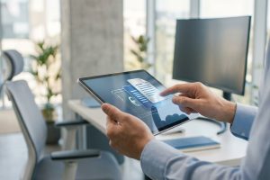Personne utilisant une tablette affichant des icônes de documents, cadenas et cloud, symbolisant la gestion sécurisée des documents RH.